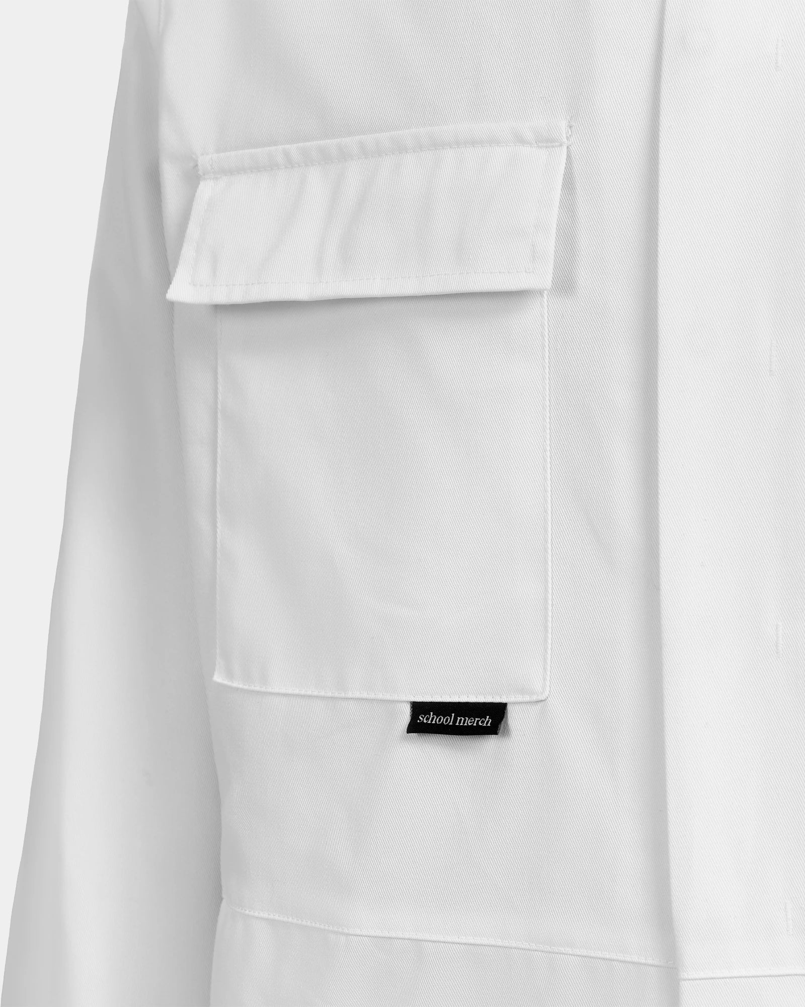 Bröstficka på vit studentoverall – praktisk detalj för studenten